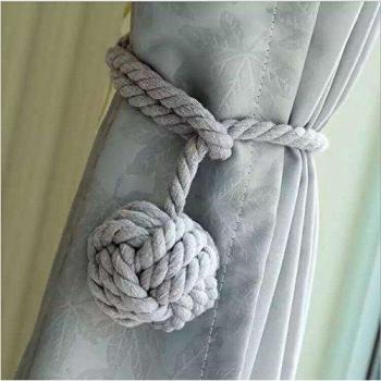 Un par de abrazaderas de cortinas artesanales con diseño de una bola de nudos al final del cordón.